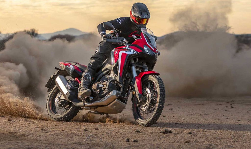 Pilota su una Honda adventure in fuoristrada tra nuvole di polvere
