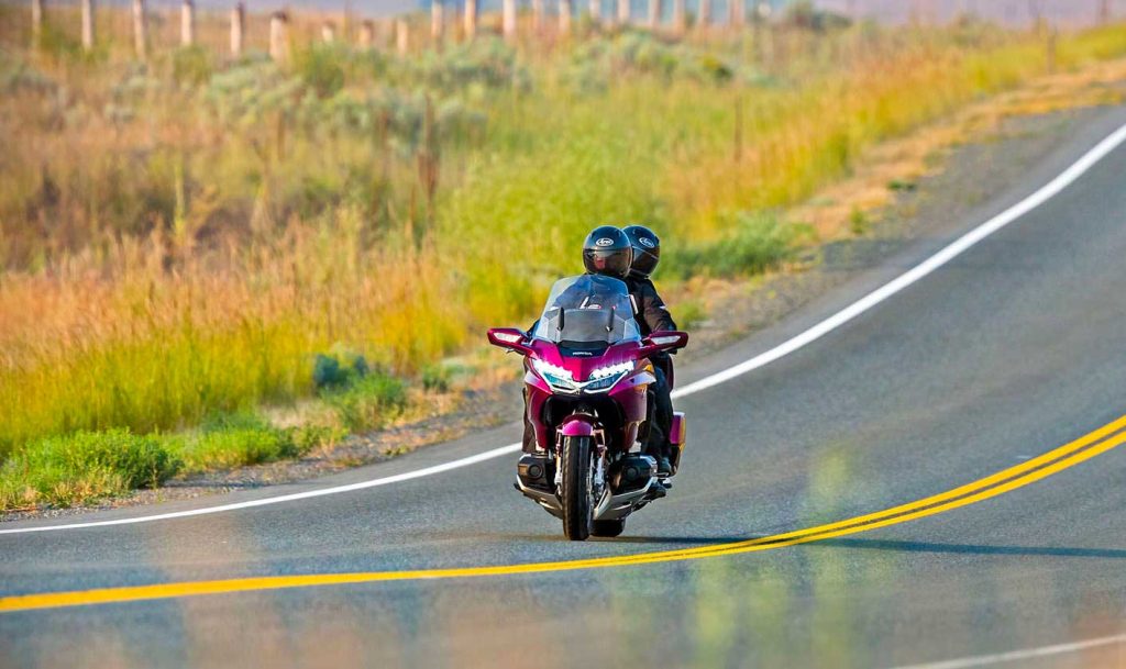 Due persone in viaggio su una Honda touring lungo una strada di campagna